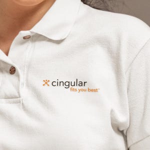May include: White polo shirt with a collar and short sleeves. The shirt features the text "cingular fits you best" in orange and black. The shirt has a buttoned placket and a brown button.