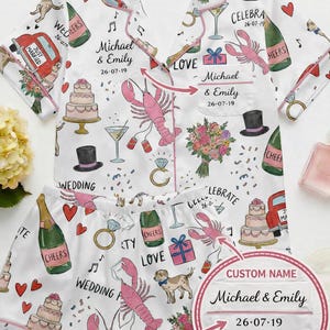 Op de afbeelding: Witte pyjamaset met een bruiloftthema, met illustraties van taarten, champagneflessen, kreeften en een rode auto. De set bevat een overhemd met knopen en een korte broek, gepersonaliseerd met de namen "Michael & Emily" en de datum "26-07-19".