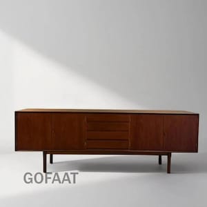 May include: A mid-century modern wooden sideboard with a warm brown finish. The cabinet features two doors on either side and a set of drawers in the center. The sideboard is supported by four slender legs. The text "GOFAAT" is visible at the bottom.