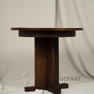 Puede incluir: Una mesa auxiliar de madera maciza de color marrón oscuro con una tapa redonda y una base de pedestal rectangular. La mesa mide aproximadamente 61 cm de alto y 61 cm de ancho. Diseño simple y minimalista.