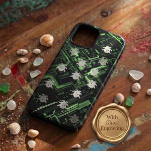 Könnte beinhalten: Eine schwarze Smartphone-Hülle mit grünem Leiterplattenmuster und weißen Schildkröten-Symbolen. Neben der Hülle befindet sich ein goldenes, kreisförmiges Wachssiegel mit dem Text With Ghost Engraving. Die Hülle hat einen Ausschnitt für die Kamera.