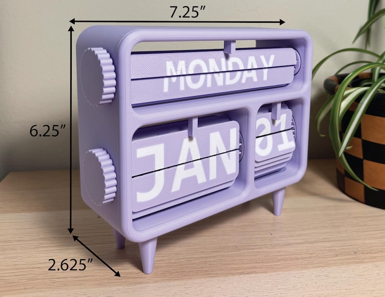 Pu&ograve; includere: Un calendario perpetuo da scrivania color lavanda. Mostra "LUNED&Igrave;" e "31 GEN" in bianco. Il calendario &egrave; largo 18,4 cm, alto 15,9 cm e profondo 6,7 cm. Ha due manopole circolari e quattro piedini.