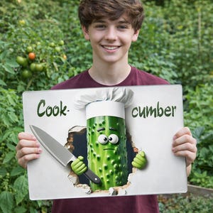 May include: A person holding a sign with the words "Cook-cumber" and a cartoon cucumber chef with a knife. The cucumber has a chef's hat and green gloves. The background is a garden.