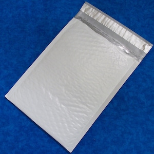 May include: White padded envelope with a silver strip along the top and bottom edges. The text "COPY MAILERS.COM  ONLINE MAILERS.COM  MAILERS.COM" is printed on the silver strip.