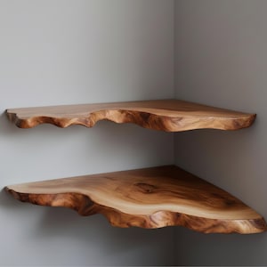 May include: Two wooden corner shelves with a natural, live edge design. The shelves are a warm brown color and appear to be made from a single piece of wood. They are mounted on a gray wall, showcasing the unique, organic shape.