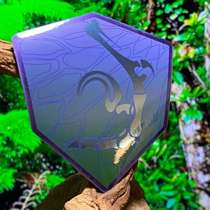 May include: A holographic sticker with a purple and blue iridescent finish. The sticker features a black silhouette of a dinosaur skeleton with a hexagonal shape.