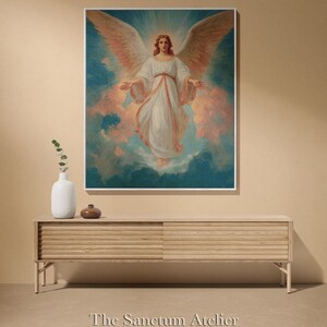 May include: A framed artwork featuring a celestial figure with large, outstretched wings. The figure is dressed in white robes, set against a backdrop of blue and peach hues. The artwork is displayed above a wooden console.