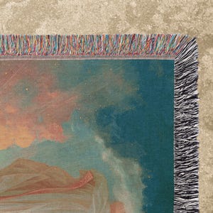May include: A woven throw blanket featuring a detail of a classical painting with a teal background and peach-colored clouds. The blanket has a fringed edge with a mix of colors, including red, blue, and orange.