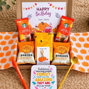 May include: A birthday gift box containing two Starbucks Pumpkin Spice Latte packets, two Border Golden Oat Crumbles packs, a yellow pumpkin-print cloth, a pumpkin keychain, a gold spoon, an orange pen, and a card reading Happy Birthday.