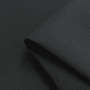 May include: Close-up of a folded piece of black fabric. The fabric has a smooth texture and appears to be a solid color. The folds create shadows and add depth to the image. The fabric is likely used for clothing or home decor.