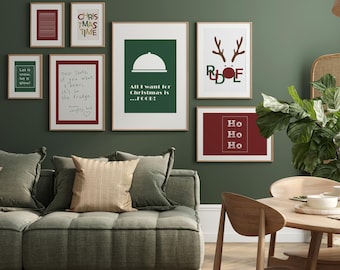 May include: A collection of framed Christmas-themed art prints. The prints feature festive text like "Christmas Time", "Let it snow", and "All I want for Christmas is...FOOD!" in various fonts and colors, including red, green, and white. The art is displayed on a green wall.