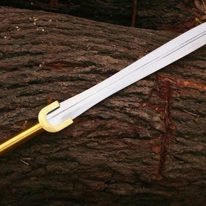 May include: A long, silver sword with a gold handle and guard rests on a textured, brown log. The blade has a central fuller and a pointed tip. The handle is cylindrical with a rounded end.