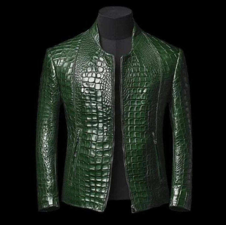 May include: A green, textured leather jacket with a crocodile skin pattern. The jacket has a stand-up collar, a front zipper, and two side pockets. The jacket is displayed on a black mannequin.
