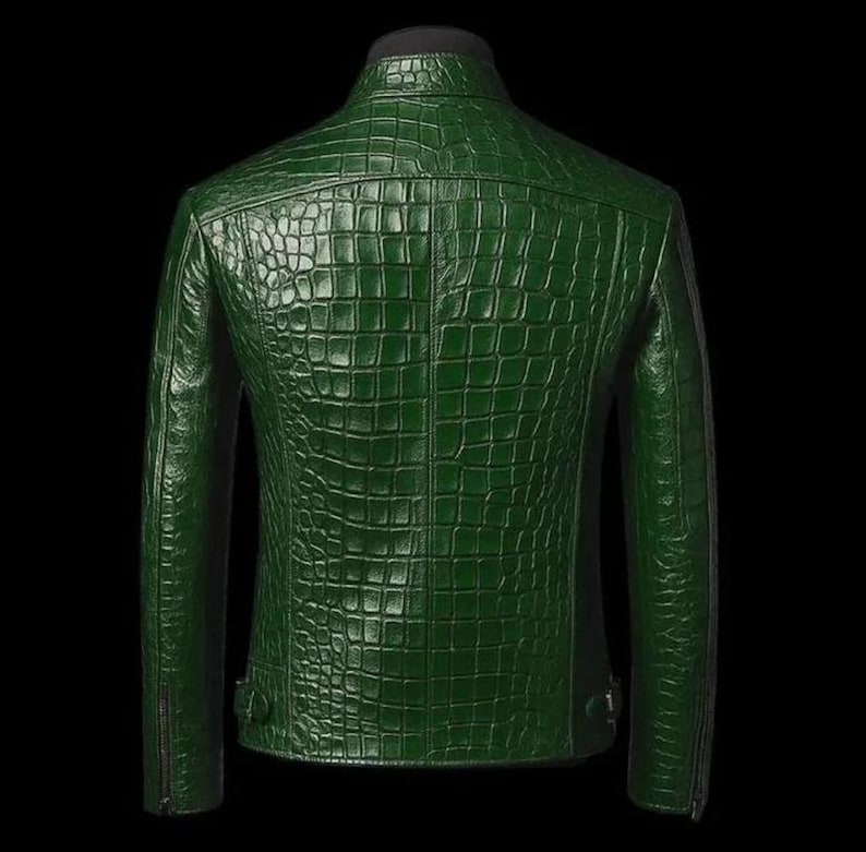 May include: A dark green leather jacket with a textured, crocodile-skin pattern. The jacket has a stand-up collar, long sleeves, and a zipper closure. The back of the jacket is visible, showcasing the detailed pattern and design.