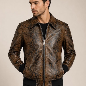 Puede incluir: Una chaqueta con estampado de piel de serpiente en tonos marrón y negro, con cuello puntiagudo, cremallera frontal plateada de longitud completa y puños y dobladillo de punto acanalado negro, sobre una camiseta negra y pantalón oscuro.