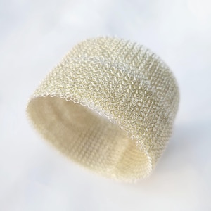 May include: A white crocheted bracelet made of small, tightly woven loops. The bracelet is flexible and has a delicate, airy appearance.