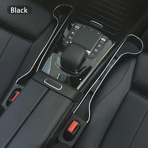 May include: Black car interior with a center console and seat. The console has a glossy black finish with silver trim and a built-in control panel. The seats are black leather. The word "Black" is in the top left corner.