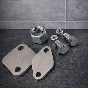 May include: A collection of metallic hardware components, including nuts, bolts, and plates. The items are arranged on a dark, textured surface, with a focus on the hexagonal shapes of the nuts and bolts. The plates have rounded corners and circular holes.