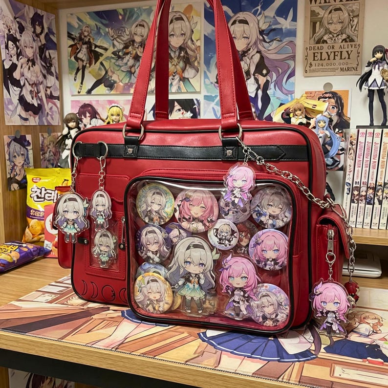 May include: A red school bag with a clear front pocket filled with character pins and acrylic charms. The bag has a black trim, silver hardware, and a chain strap. Additional charms hang from the bag. Anime-themed merchandise.