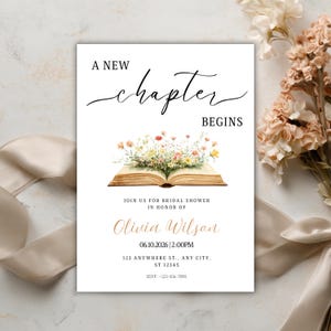 May include: White invitation card with the text "A New Chapter Begins" in elegant script. The card features an open book illustration with floral accents, and event details including a name, date, time, and address.