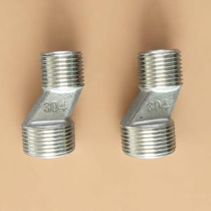 May include: Two silver-colored metal offset pipe connectors with threaded ends. Each connector features a central angled body section with the number 304 clearly embossed on the side, indicating the stainless steel material grade used for construction.