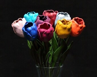 May include: A bouquet of ten leather tulips in a glass vase. The tulips are in various colors, including pink, blue, purple, red, yellow, and orange.
