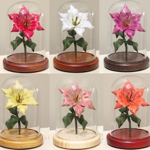 May include: Six glass cloches with wooden bases display six different colored paper flowers. The flowers are red, white, yellow, pink, orange, and a darker pink. The cloches are all the same size and shape.