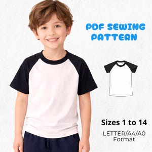 May include: A child wearing a white and black raglan t-shirt. The image includes a diagram of the shirt and text that reads "PDF Sewing Pattern" and "Sizes 1 to 14". The shirt has black sleeves and a white body.
