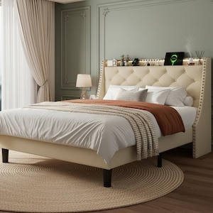 May include: A cream-colored upholstered bed frame featuring a tufted headboard with nailhead trim and a built-in storage shelf along the top. The bed is dressed with white pillows, a white duvet, and a folded rust-colored throw blanket on top.