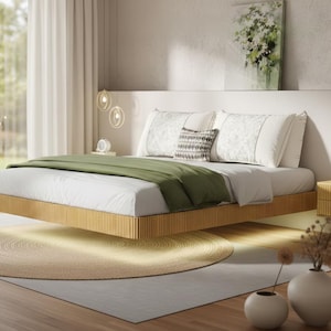 May include: A modern bedroom scene featuring a floating bed with a light wood frame and a green blanket. The bed is made with white linens and decorative pillows. A round rug sits beneath the bed, and a large window offers a view of the outdoors.