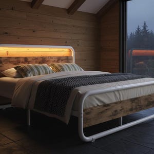 May include: A modern bed frame with a white metal structure and a wooden headboard. The headboard has a warm, glowing light. The bed is made up with pillows, a blanket, and a duvet. The room has wooden walls and a large window.