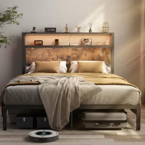 May include: A modern bed frame with a wooden headboard, featuring a built-in shelf with decorative items and a light. The bed is made up with pillows, a blanket, and a throw. A robotic vacuum cleaner is on the floor.
