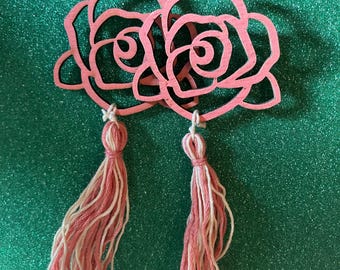 White and coral colored tassel earrings on wooden rose wood cut outs.