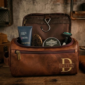 May include: A brown leather toiletry bag with a zipper closure and the name Dustin printed on the front. The open bag contains a tube of Men Oil Control Dustin cream, a round tin of Peppermint Shaving Soap, a shaving brush, and a razor.