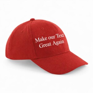 May include: A red baseball cap with a curved brim. The cap features the white text "Make our Text Great Again" embroidered on the front. The cap has a rounded crown and a small button on top.