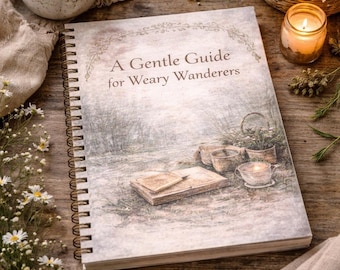 May include: A spiral-bound book titled "A Gentle Guide for Weary Wanderers" rests on a wooden surface, next to a cup of tea, a lit candle, and a basket of flowers. The book's cover features a watercolor illustration of a serene outdoor scene.