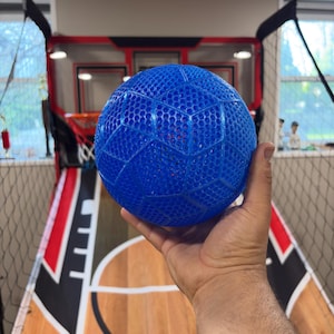 May include: A bright blue, spherical ball featuring a textured, honeycomb-like lattice pattern across its entire surface. The ball is constructed from a semi-translucent, flexible material that reveals a hollow interior structure through the mesh.