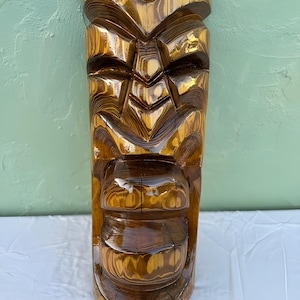 以下が含まれることがあります： 光沢仕上げの、手作りの木製ティキマスク。 マスクは、幾何学的な形状と顕著な顔を持つ、詳細な彫刻デザインが特徴です。 木目は見え、茶色とタンの自然な色を示しています。