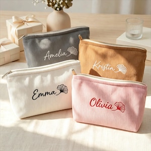 Peut inclure: Quatre trousses de maquillage en velours côtelé gris, beige, blanc et rose, chacune avec un nom brodé dans une couleur contrastante. Les trousses ont une fermeture éclair et un motif de feuille brodé.