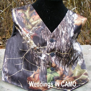 May include: Camouflage patterned waistcoat with black buttons. The waistcoat is made of satin and has a V-neck. The text "Weddings IN CAMO" is printed on the bottom of the waistcoat.