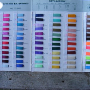 May include: A colour chart of woven-edge satin ribbon in various colours and widths. The chart includes the ribbon's width in inches and millimetres, as well as the width number. The chart also includes information about the ribbon's care, such as no ironing, machine washable, machine dry, less than 2% shrinkage, and colourfast.
