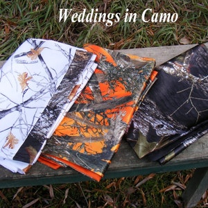 May include: Three different camouflage fabric swatches, one white, one orange and black, and one black and brown. The fabrics are folded and arranged on a wooden surface. The text "Weddings in Camo" is visible at the top of the image.
