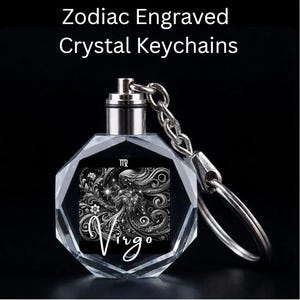 May include: A clear, faceted crystal keychain with a silver-colored metal top and chain. The keychain features a black and white Virgo design with the word "Virgo" in white script. The text "Zodiac Engraved Crystal Keychains" is at the top.