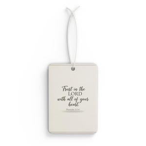Puede incluir: Un ambientador rectangular blanquecino con una cuerda blanca para colgar. La parte delantera presenta el texto "Trust in the LORD with all of your heart. Proverbs 3:5-6" en escritura negra. El ambientador tiene un diseño sencillo y elegante.