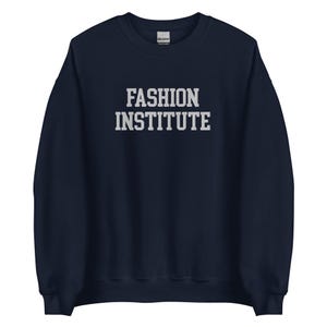 Puede incluir: Sudadera azul marino con el texto "FASHION INSTITUTE" en letras blancas. La sudadera tiene cuello redondo y mangas largas. El logotipo de Gildan es visible en la nuca.