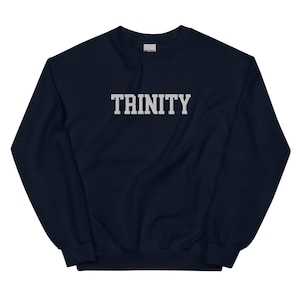 May include: A navy blue sweatshirt with the word "TRINITY" printed in white block letters across the chest. The sweatshirt has a crew neck and long sleeves. The fabric appears to be a soft, comfortable material.