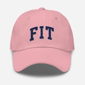 May include: A pink baseball cap with the word "FIT" embroidered in navy blue block letters across the front. The cap has a curved brim and an adjustable strap at the back.