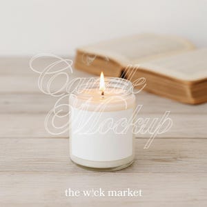 May include: A lit candle in a clear glass jar with a white label, set on a light wood surface. The flame flickers brightly. An open book is in the background. The text "the wick market" is at the bottom.
