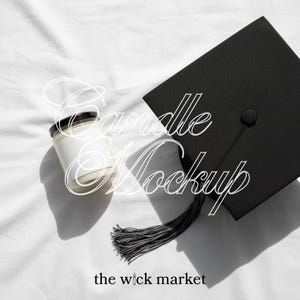 May include: A black graduation cap with a tassel next to a white candle in a glass jar with a black lid. The text "Candle Mockup" is overlaid on the image, along with "the wick market".