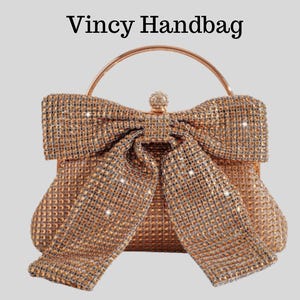 May include: A gold-toned handbag featuring a large bow made of sparkling embellishments. The bag has a rounded shape and a metal handle. The text "Vincy Handbag" is at the top of the image.